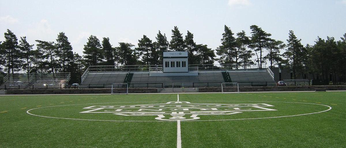 A wide angle shot of Justin Chiu Stadium shows the logo in center field and a large set of stands for spectators. 